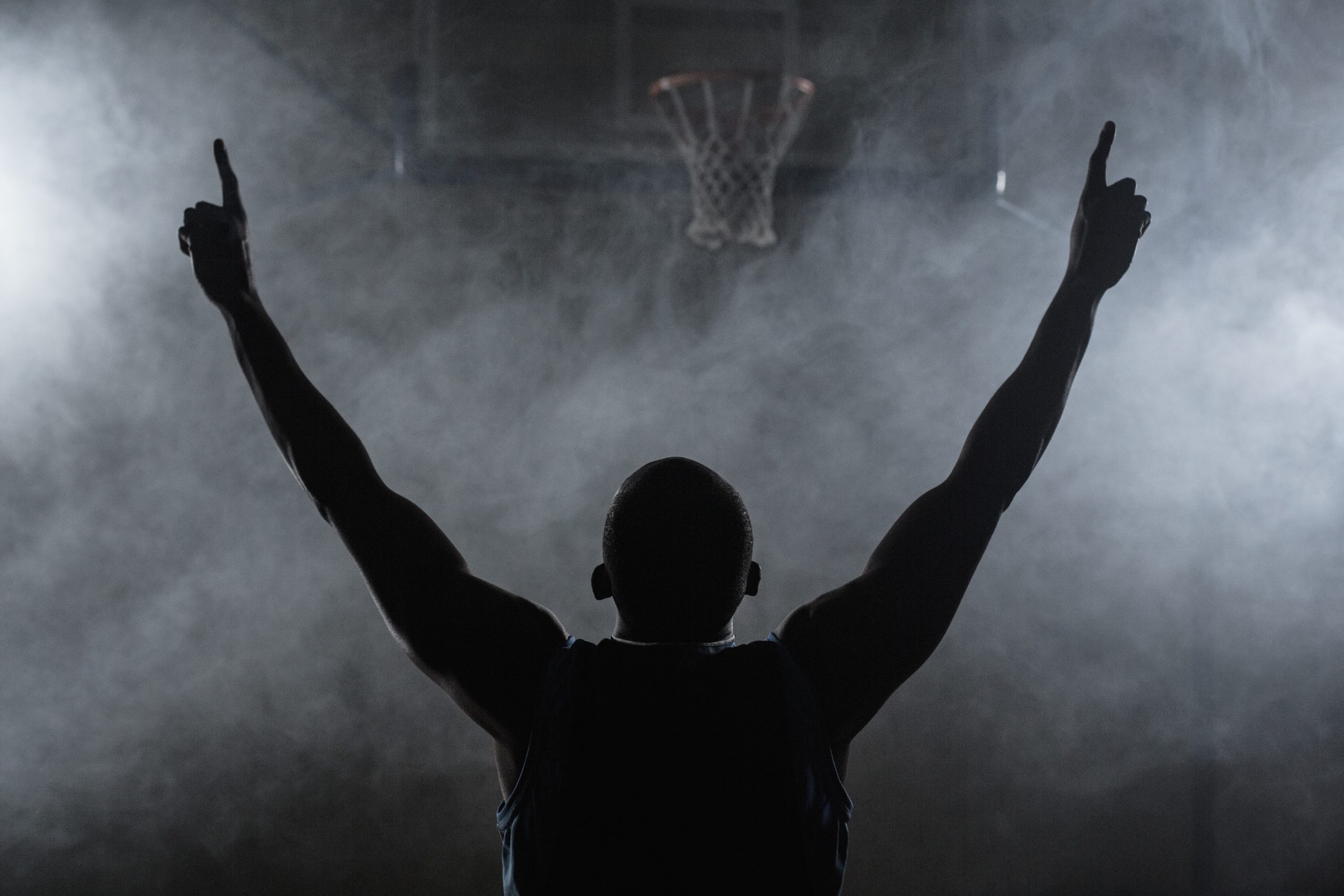 Rear view of a basketball player with his arms in the air in a gymnasium